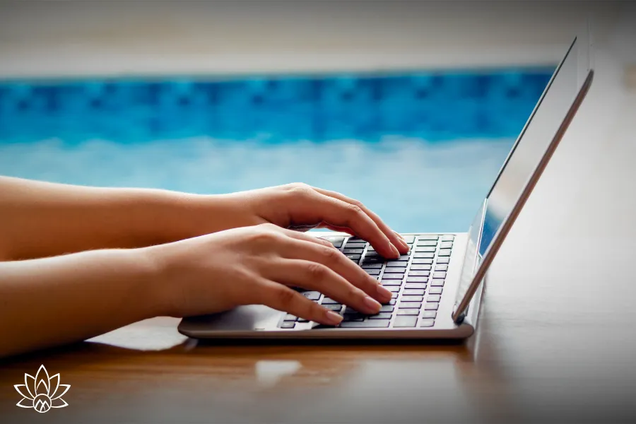 Hands typing on a laptop, representing focused work, productivity, and creating a positive employee experience in the workplace