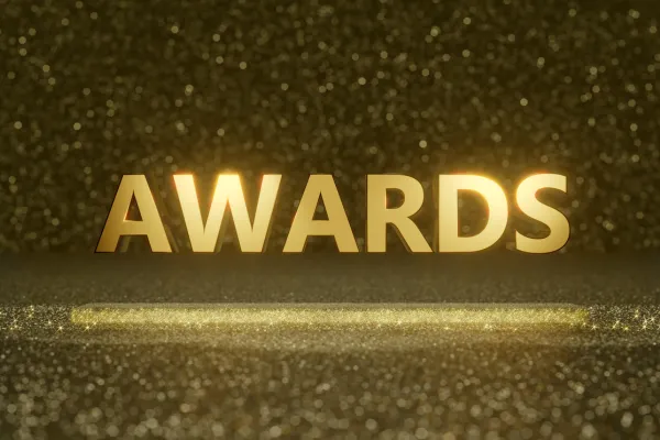 The image shows the word Awards in capitals letters coloured gold floating in the air above the ground with gold glitter falling all around it.