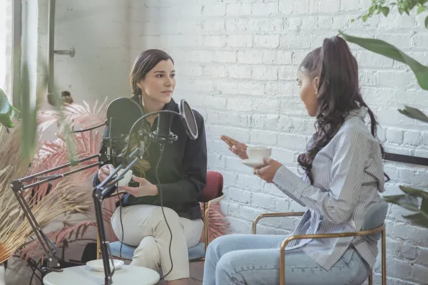 A female journalist is interviewing a female expert in a relaxed indoor setting