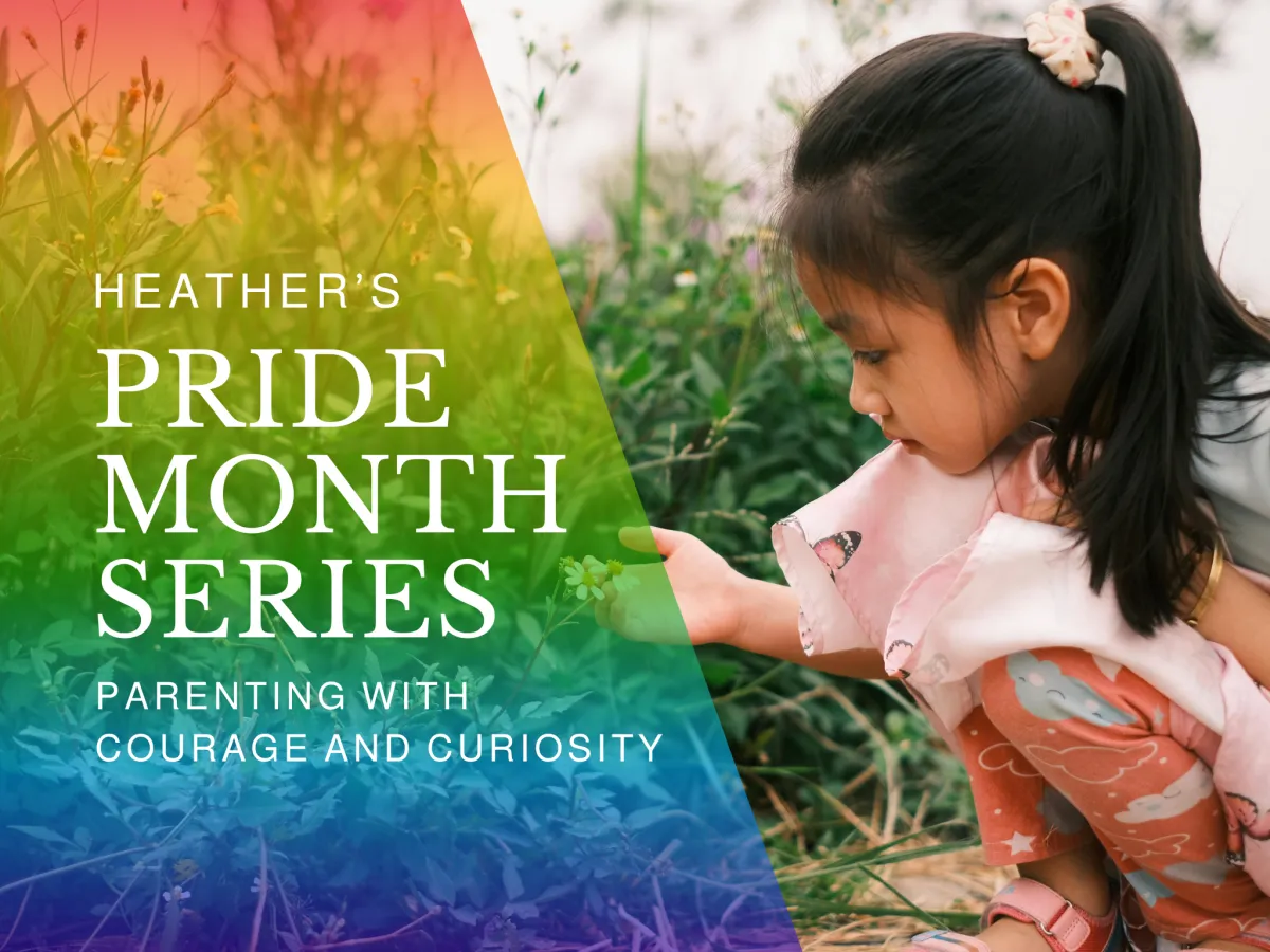 A young child crouches in a field, gently observing a flower. A soft rainbow overlay and text read “Heather’s Pride Month Series: Parenting with Courage and Curiosity.”