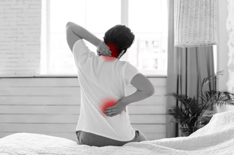 Man waking up with joint pain in his back and his neck.
