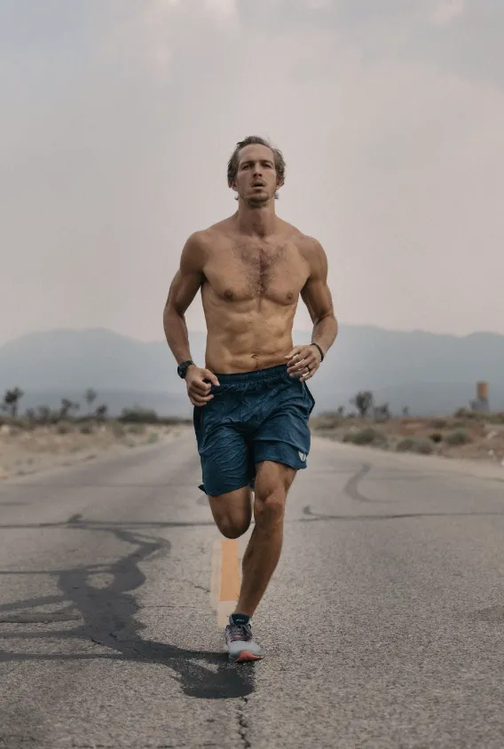 Shirtless man running with perseverance on a long road.