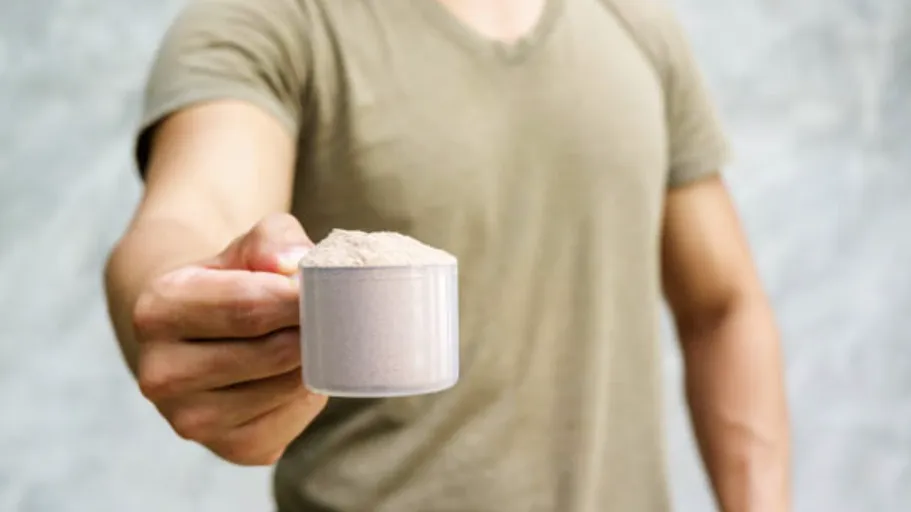 Man holding scoop of protein powder to the audience