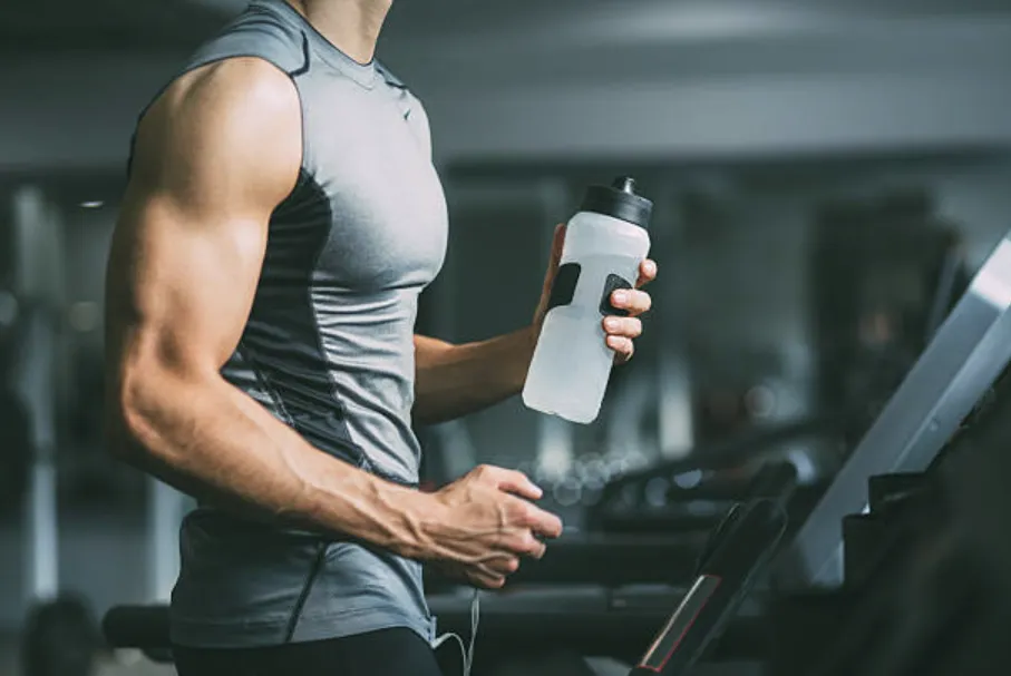 Fit man on a treadmill holding a bottle of water.
