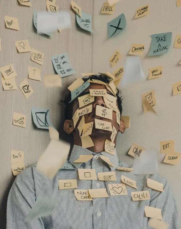 Busy man covered in sticky notes with too many responsibilities and not enough time.