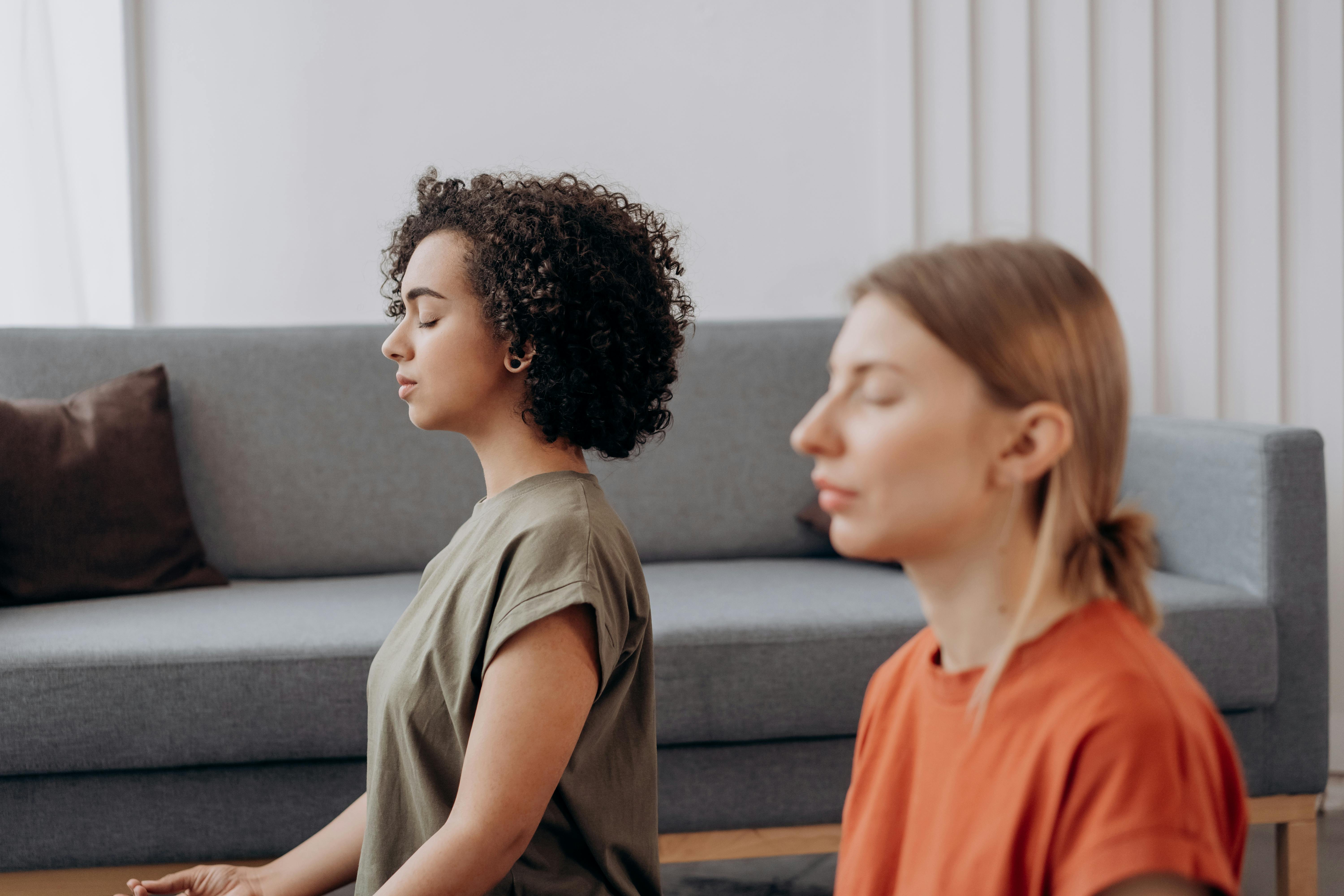 Two women practicing mindfulness meditation indoors, symbolizing calm, emotional balance, and mental well-being during perimenopause and menopause.