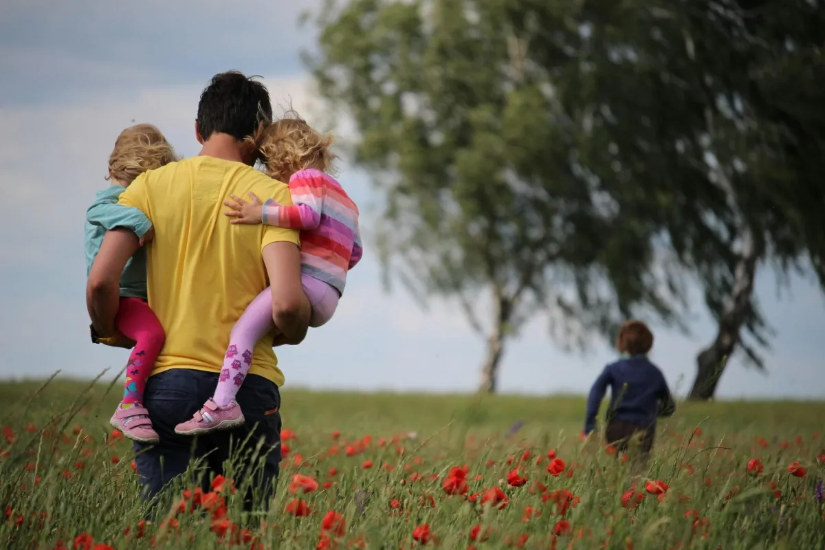 Man walking across field with children