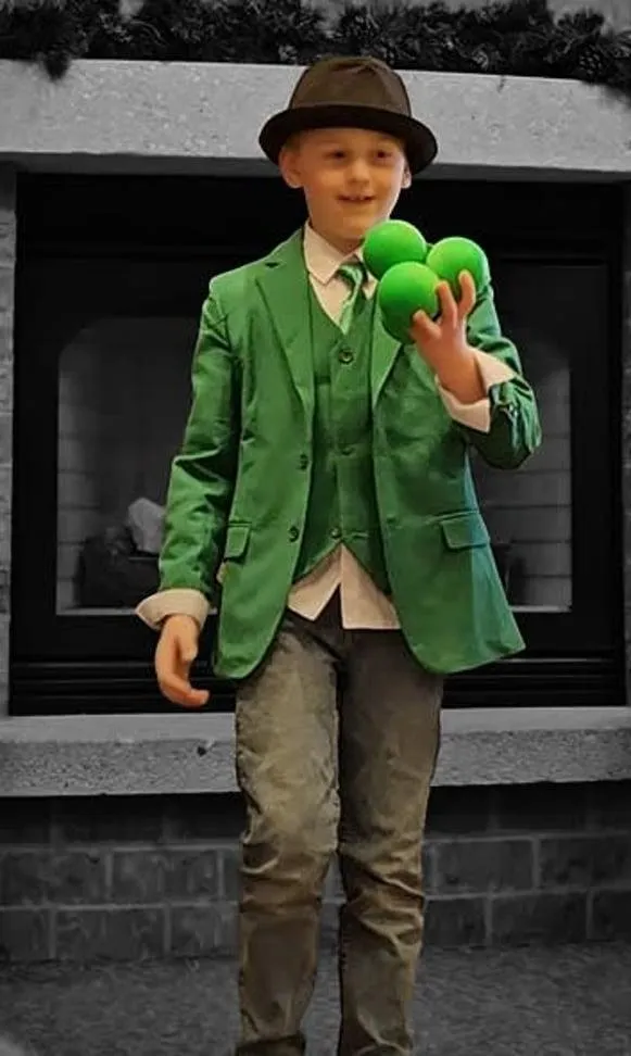 A young juggler wearing green suit.