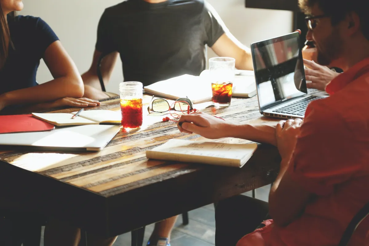 people sitting around a cluttered wooden table