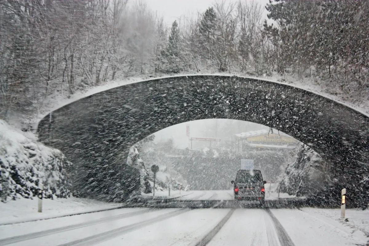 car driving under bridge during snow storm