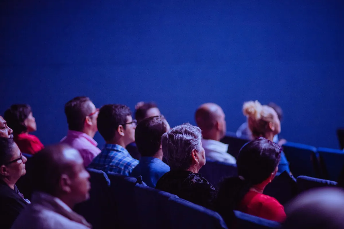 a group of people sitting in a dim room watching a seminar