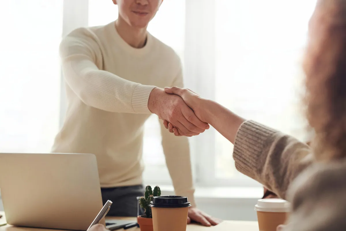 Man behind desk shaking hands with client