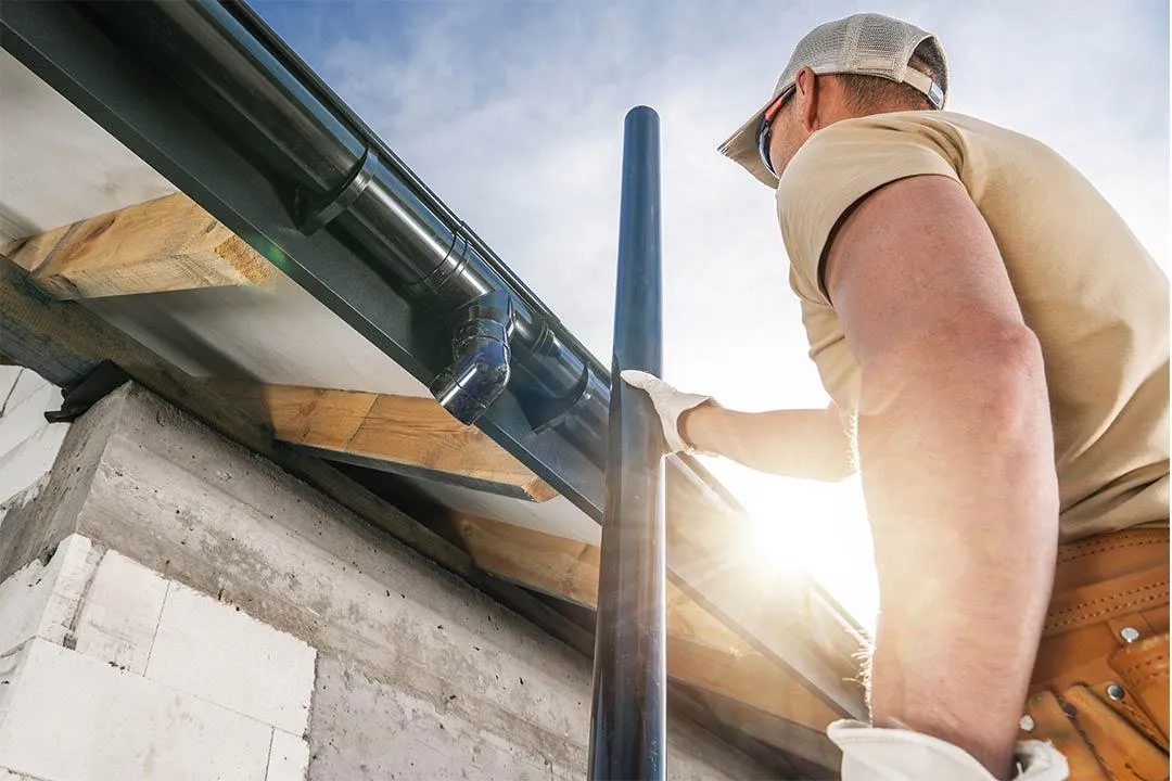 A roofing contractor installing a new gutter.