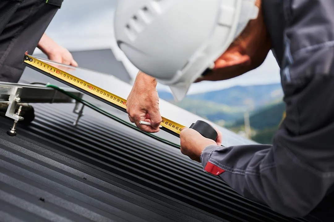 A contractor measures a roof to ensure accurate material orders.