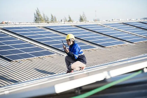 Roofer on solar roof inspection holding a two-way radio