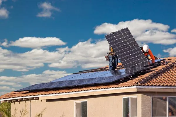 2 roofers installing solar panels in a residential roof