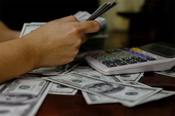 Counting of money with a background of scattered bills and a calculator