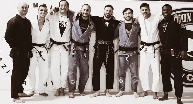 Group of men in martial arts uniforms, arms around each other, posing for a photo.