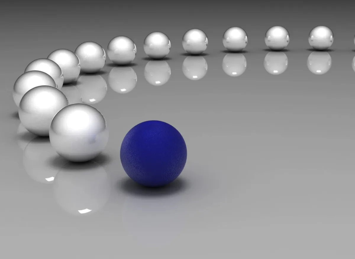 A single blue sphere leading a line of silver spheres, symbolizing strategic leadership, clarity, and differentiation in high-performing organizations.