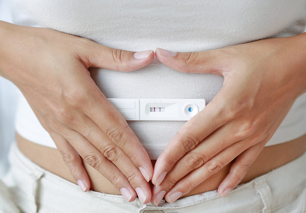 close up of hands resting on pregnant belly
