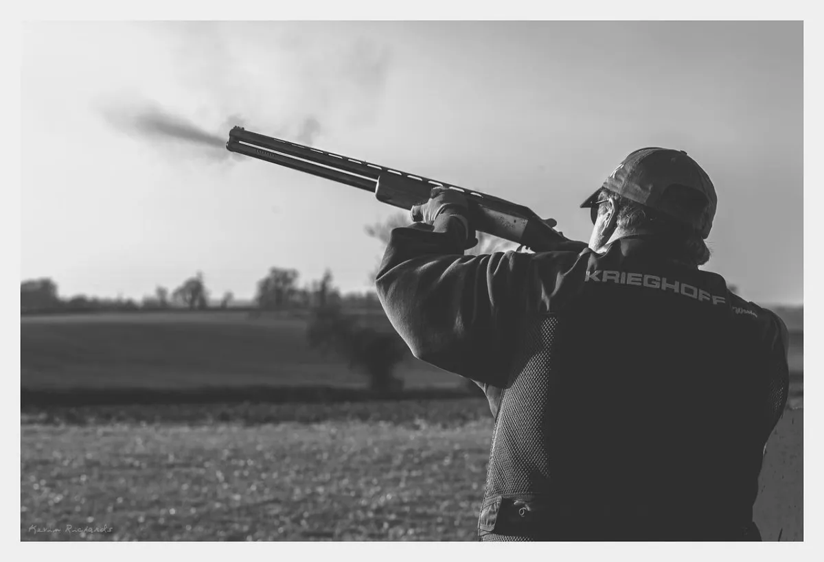 a person shooting a rifle at a clay pigeon