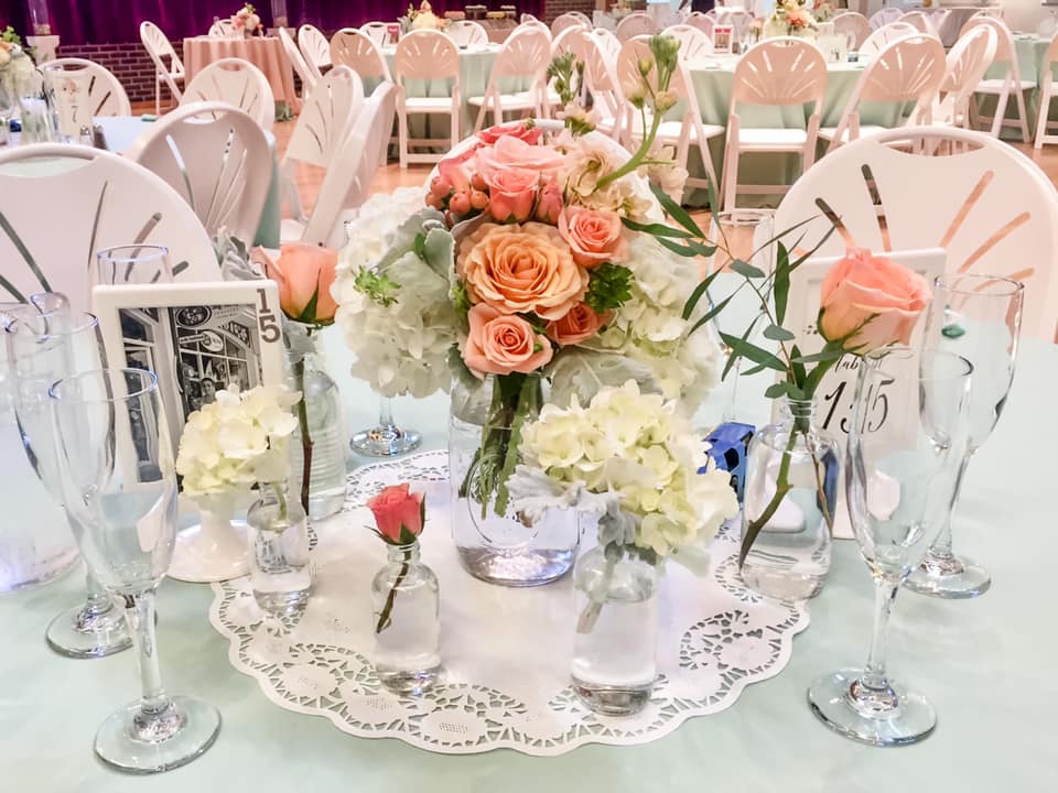 Wedding brunch reception table centerpiece with peach and pink roses, white hydrangea, and feather eucalyptus.