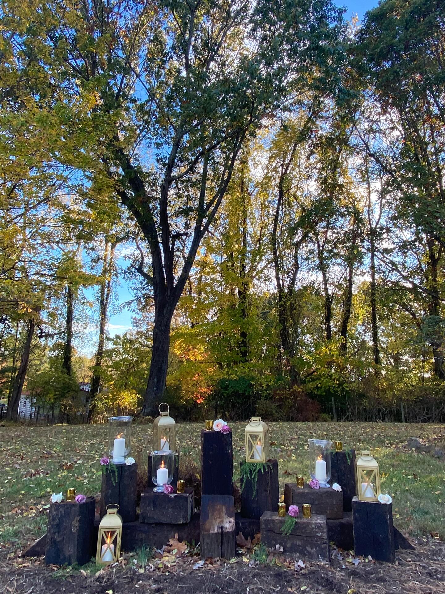 Fall wedding ceremony décor featuring lanterns, candles, and floral accents arranged on stacked wood blocks in an outdoor New River Valley setting