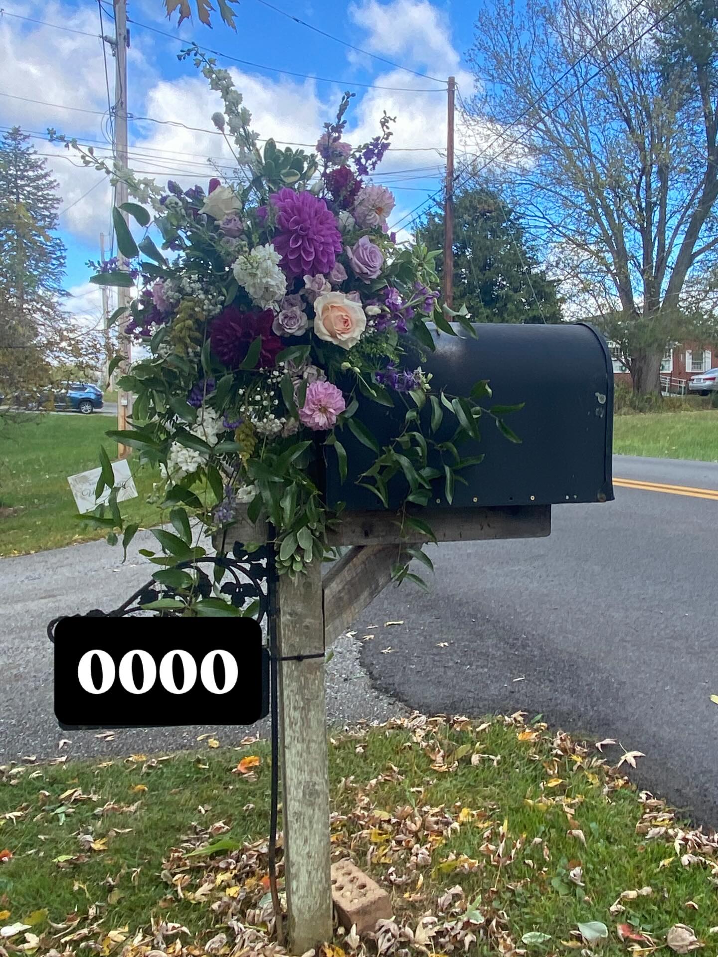 Seasonal floral arrangement with dahlias and greenery on a mailbox