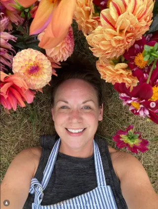 Seasonal blooms surrounding the designer at Efflorescence Floristry in the New River Valley, reflecting a joyful, hands-on approach to sustainable floral design.