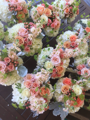 Bouquets with creamy white hydrangea, Peach, Pink, and orange roses, and cream and peach stock.