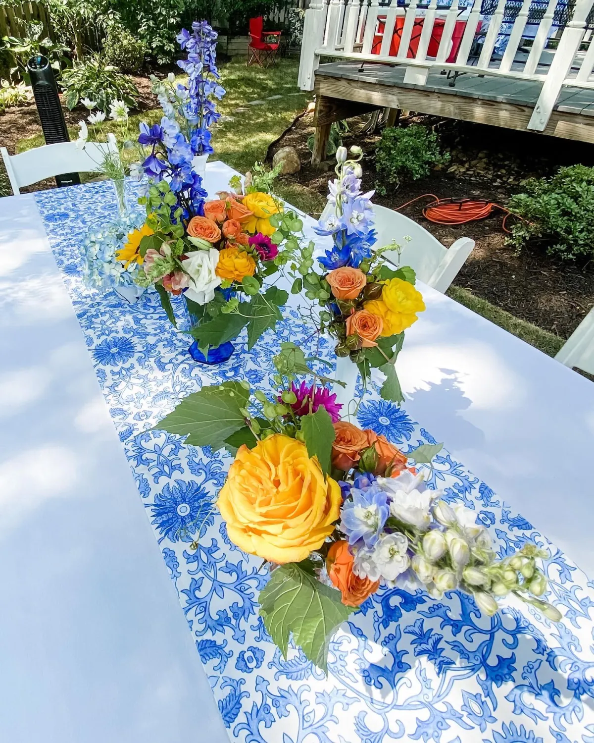 Colorful flowers in a collective centerpiece on white table with cobalt blue floral table runner.