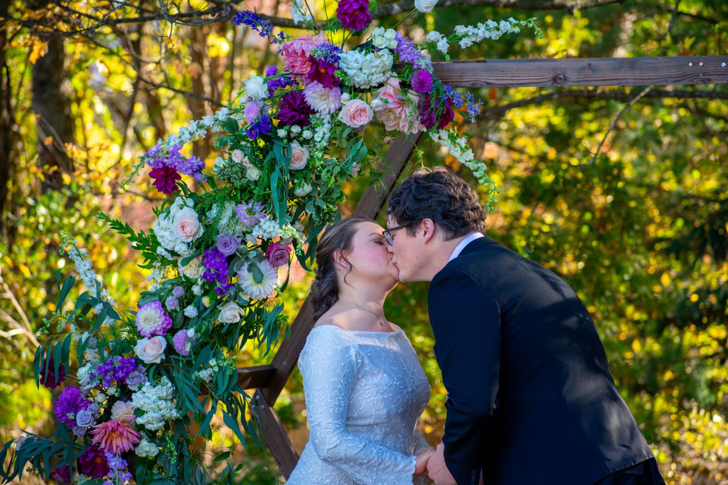 “Seasonal fall wedding floral installation featuring dahlias, roses, and locally sourced blooms arranged on a wooden arbor in the New River Valley.