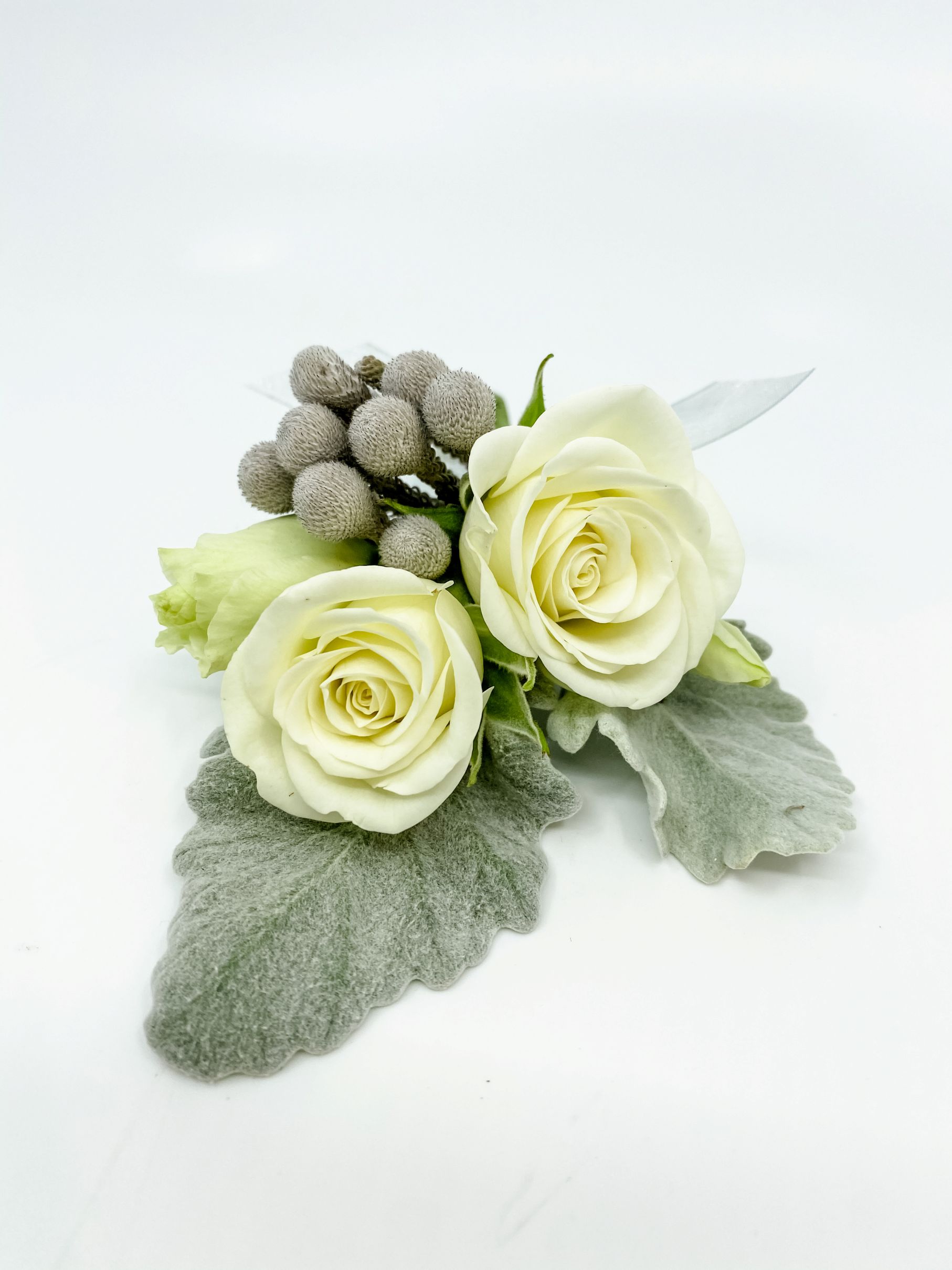 Companion boutonniere with spray roses, lisianthus, and silver texture and dusty miller leaves