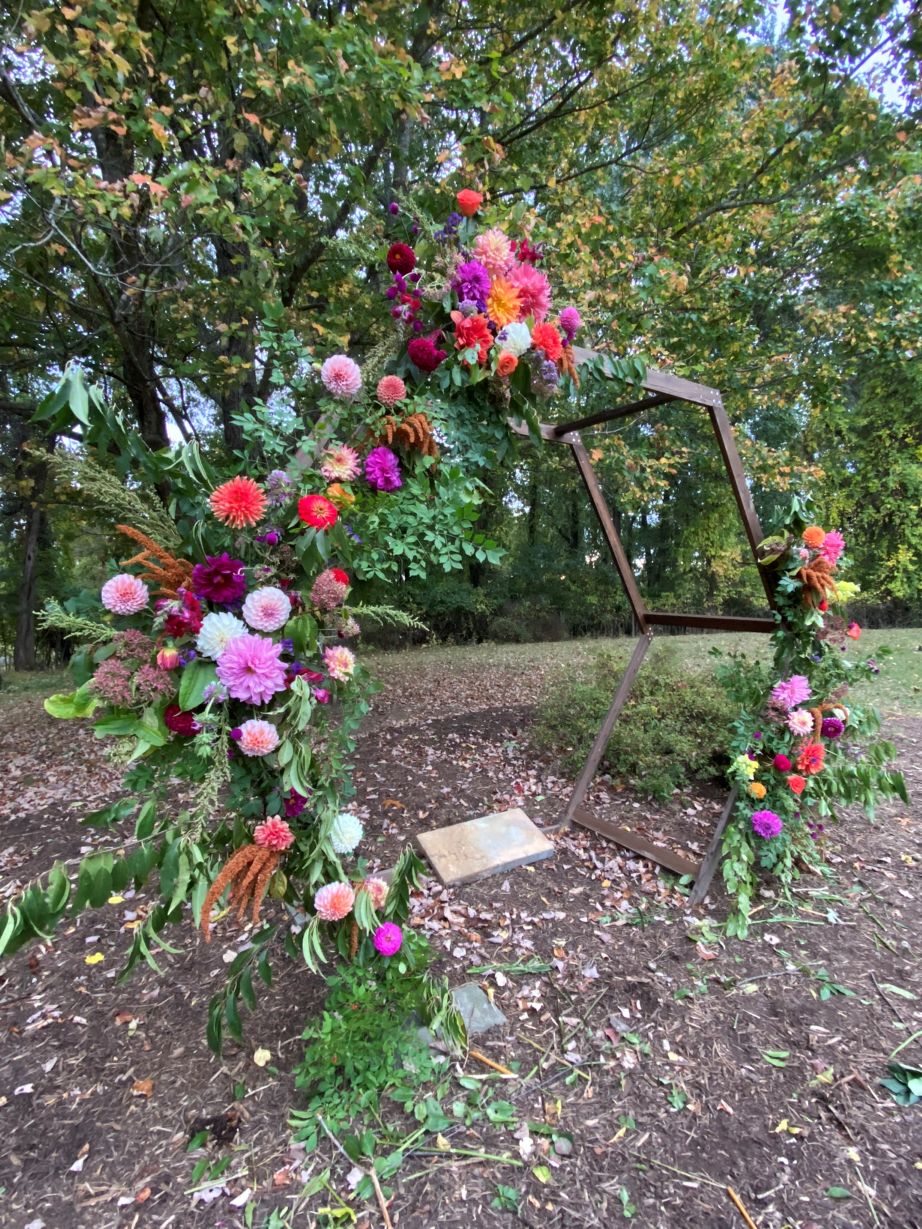 Angel guides students in creating a floral arch of fall flowers, colorful dahlias and mixed greenery.