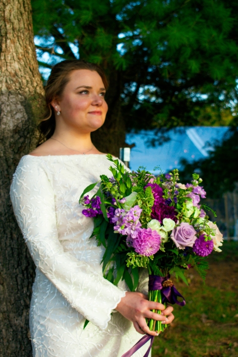 Bride holding a seasonal wedding bouquet with dahlias and roses while sharing a heartfelt embrace during a New River Valley wedding