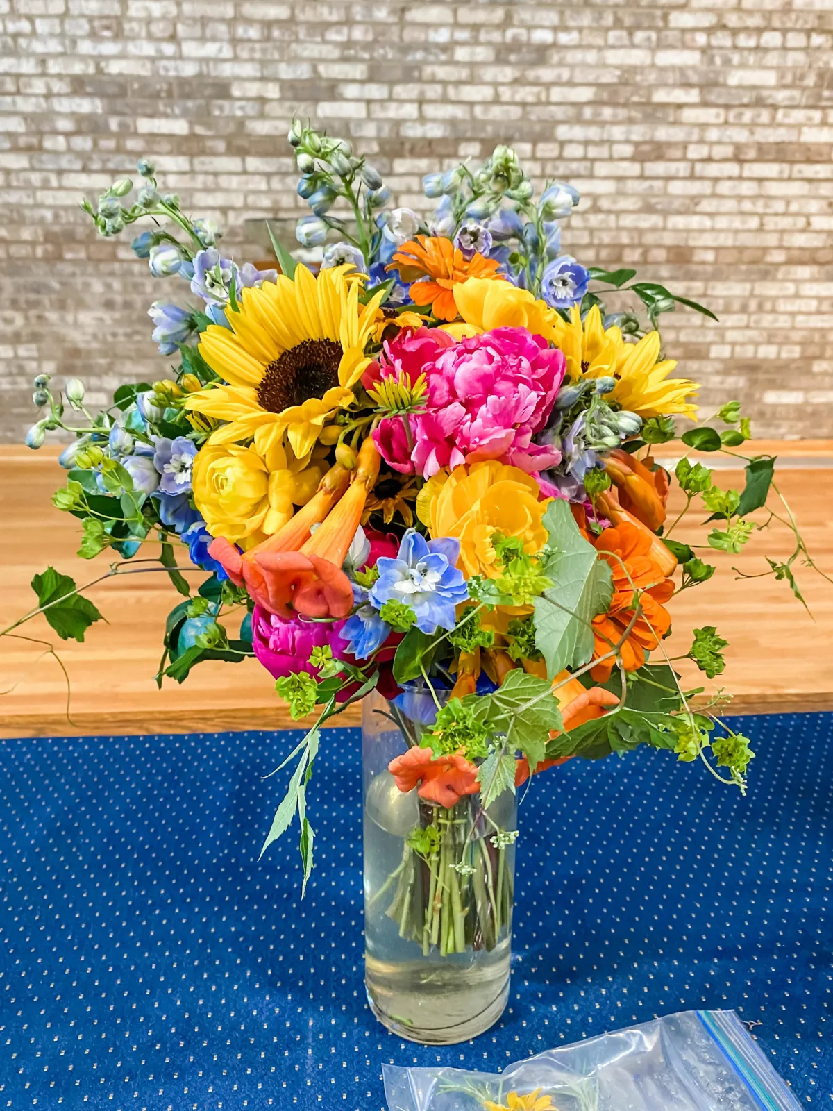 colorful bridal bouquet with sunflower, peonies, ranunculurs, trumpet flower, zinnias, delphinium, and trumpet flower vine
