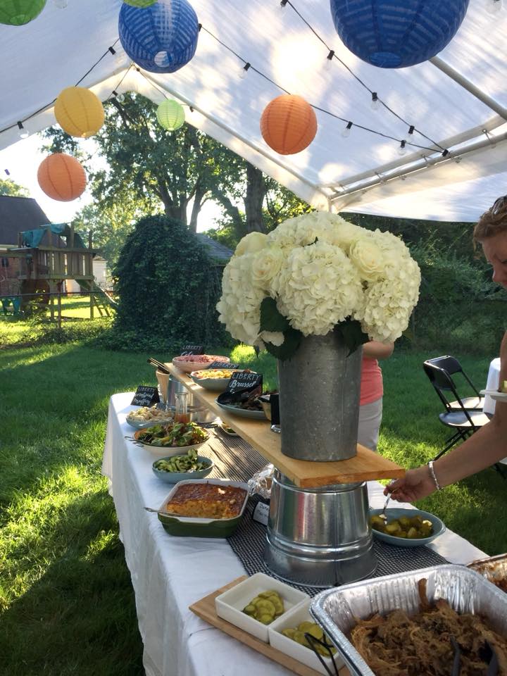 White hydrangea and roses in a tall galvanized bucket for a backyard BBQ buffet.