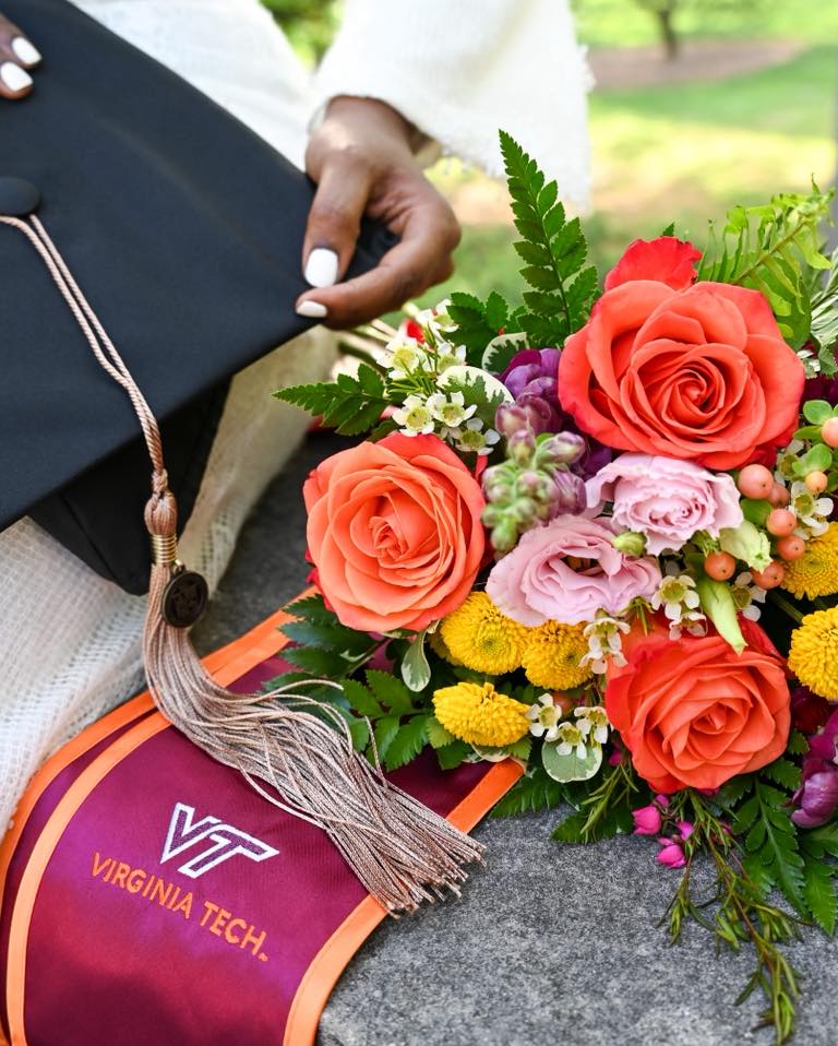 Hand-tied bouquet in for Virginia Tech graduation, orange roses, pink lisianthus, yellow button poms, maroon snapdragons, waxflower, mixed greens