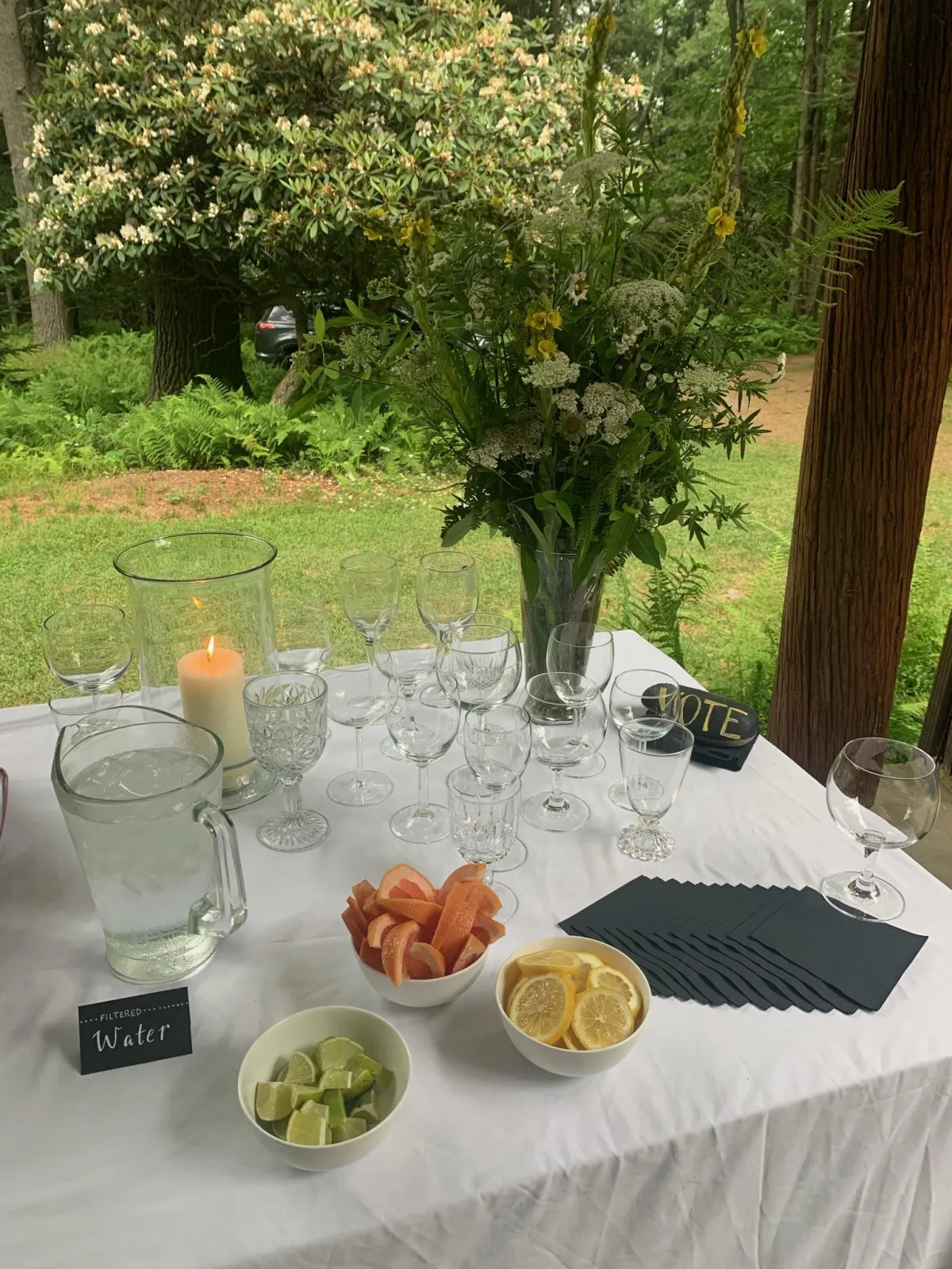 A large Beverage Station floral arrangement made of July foraged flowers and foliage in white and yellow with natural greens.