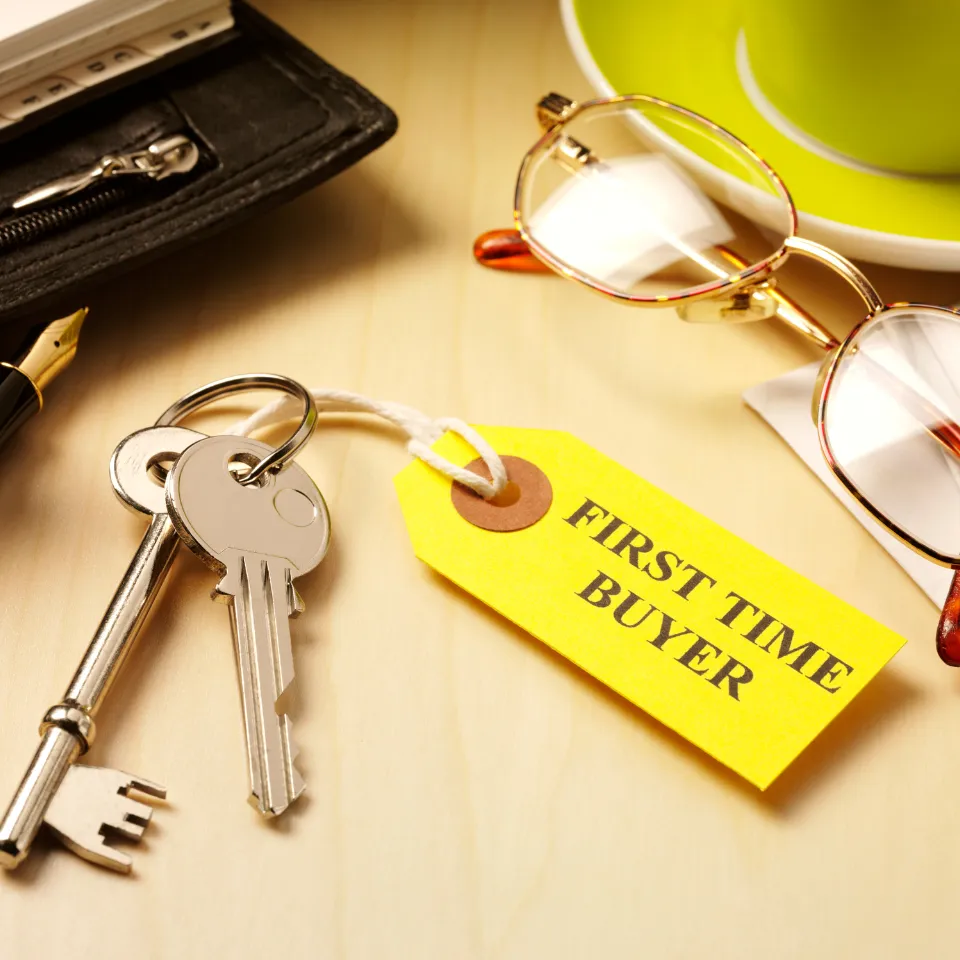 First-time homebuyers reviewing budget options with a real estate agent, with price tags on different home styles.