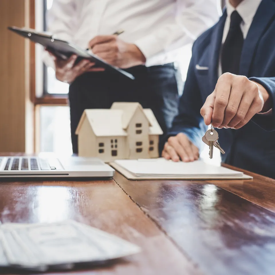 Homebuyer reviewing strategies with a real estate agent, with rising interest rate icons and a house in the background.