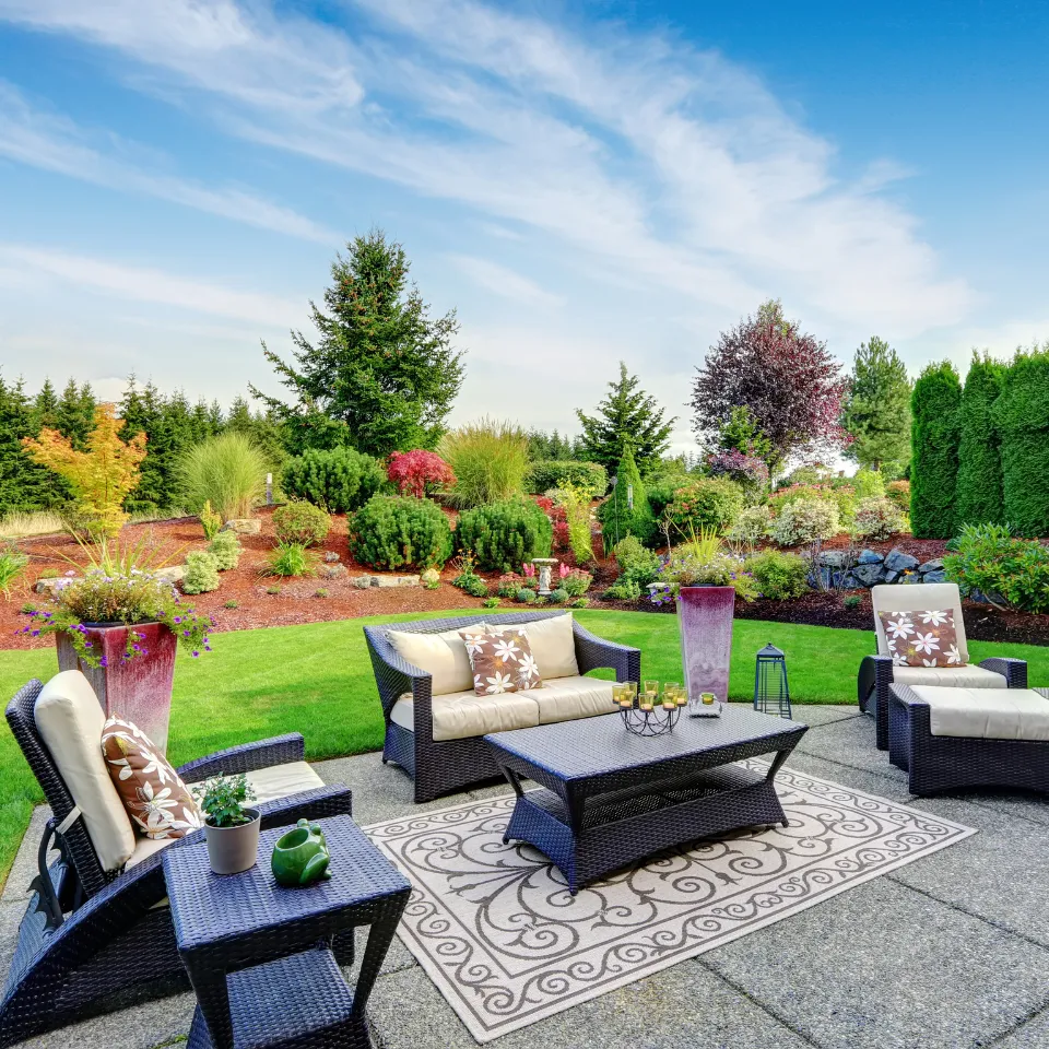 Elegant backyard with manicured hedges, outdoor lighting, and seasonal plants in a high-end landscape design.