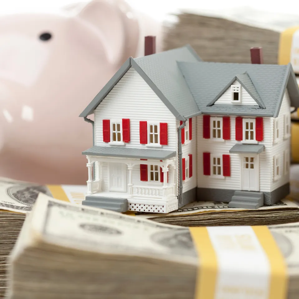 Piggy bank, calculator, and home icon surrounded by floating percentage signs and dollar symbols.