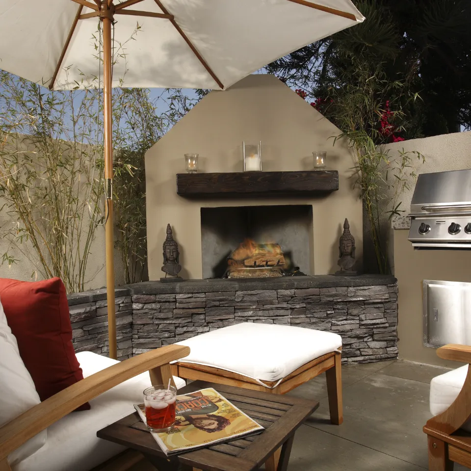 Beautiful backyard with an outdoor kitchen, patio seating, fireplace, garden lights, and lush landscaping.