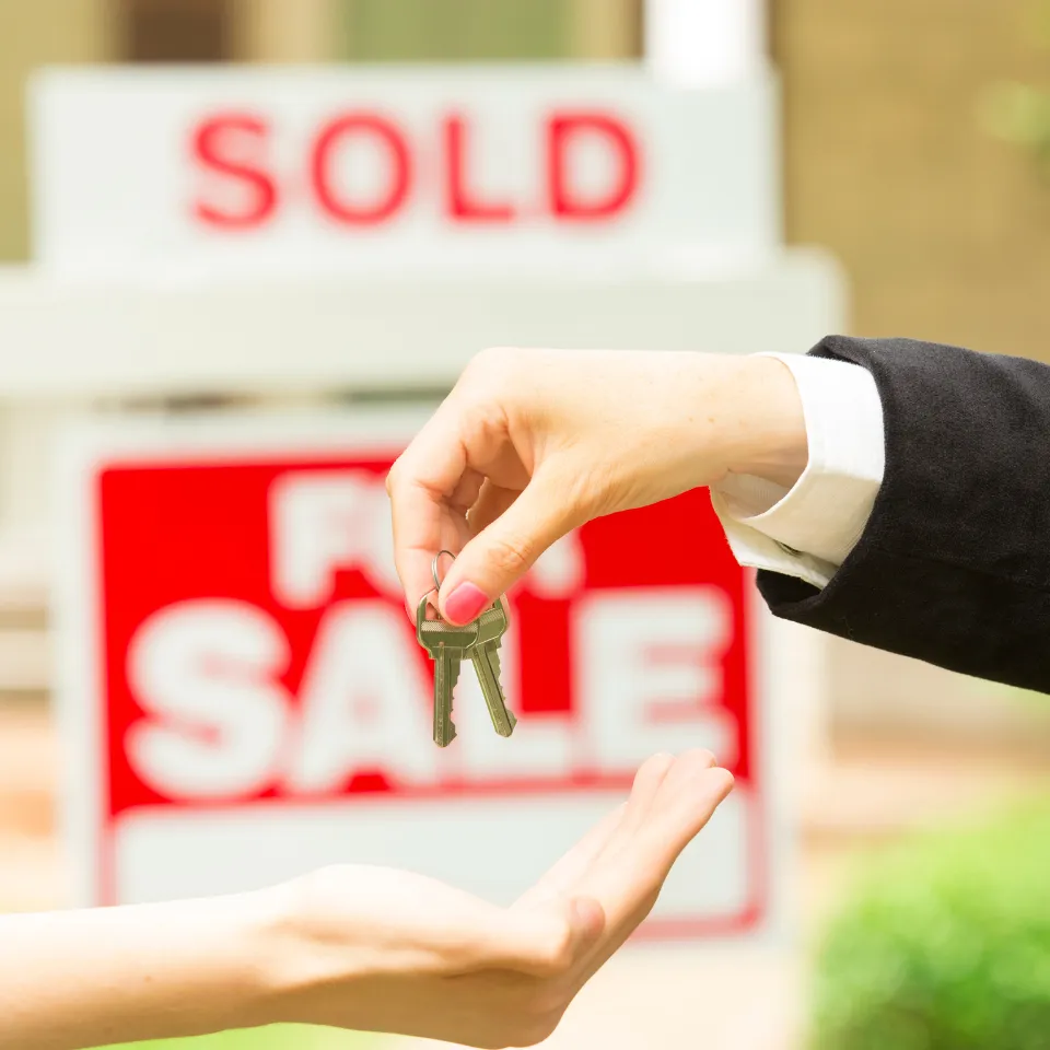 Real estate agent showing a home to buyers with a “Sold” sign out front and market data chart overlay.
