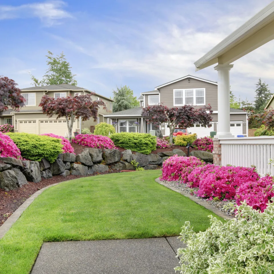 Summer open house with welcoming front porch, fresh landscaping, and vibrant flowers.