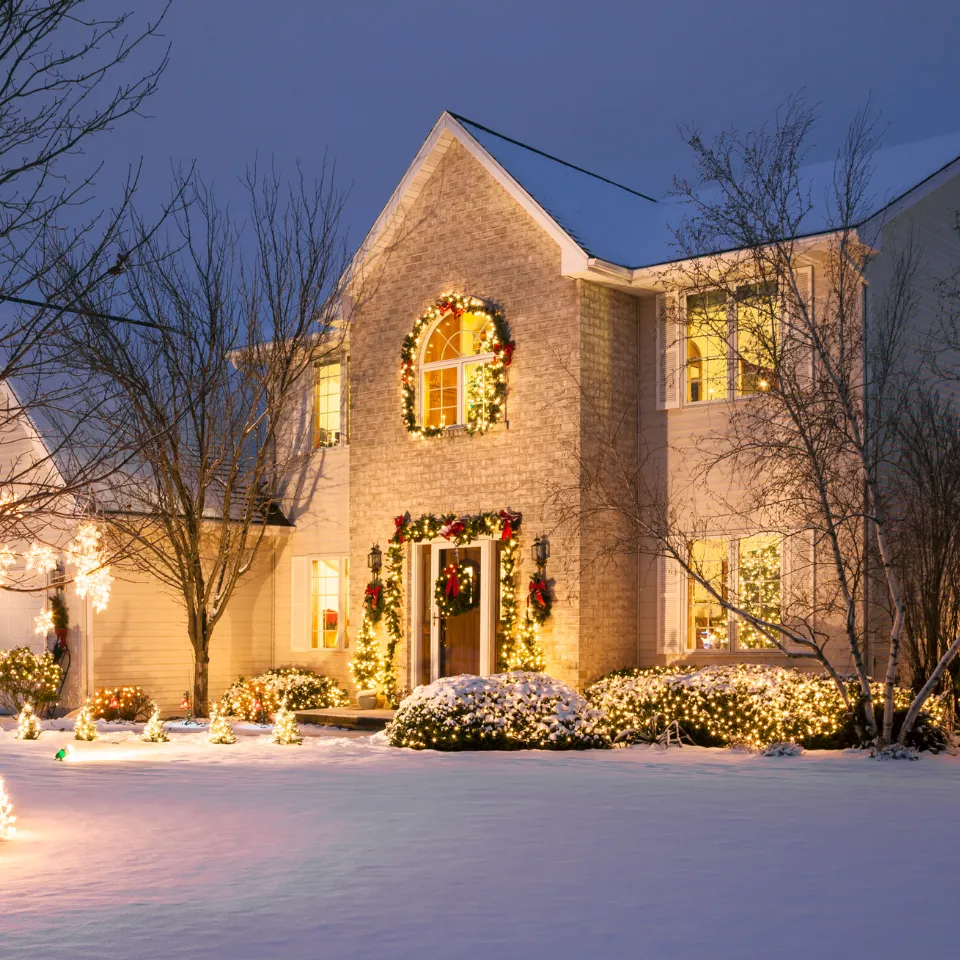 Snow-covered home with holiday decor and warm interior glow, ready for winter sale.