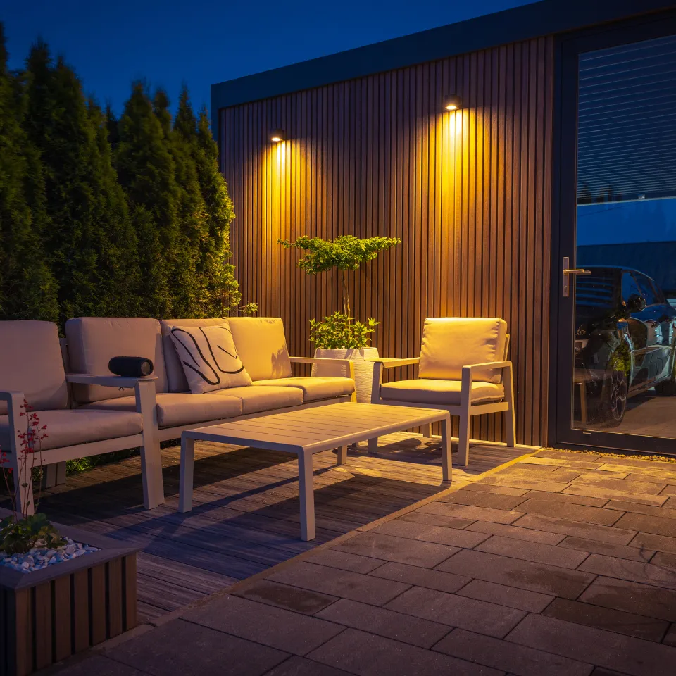 Stylish backyard with cozy seating, string lights, greenery, and a water feature.