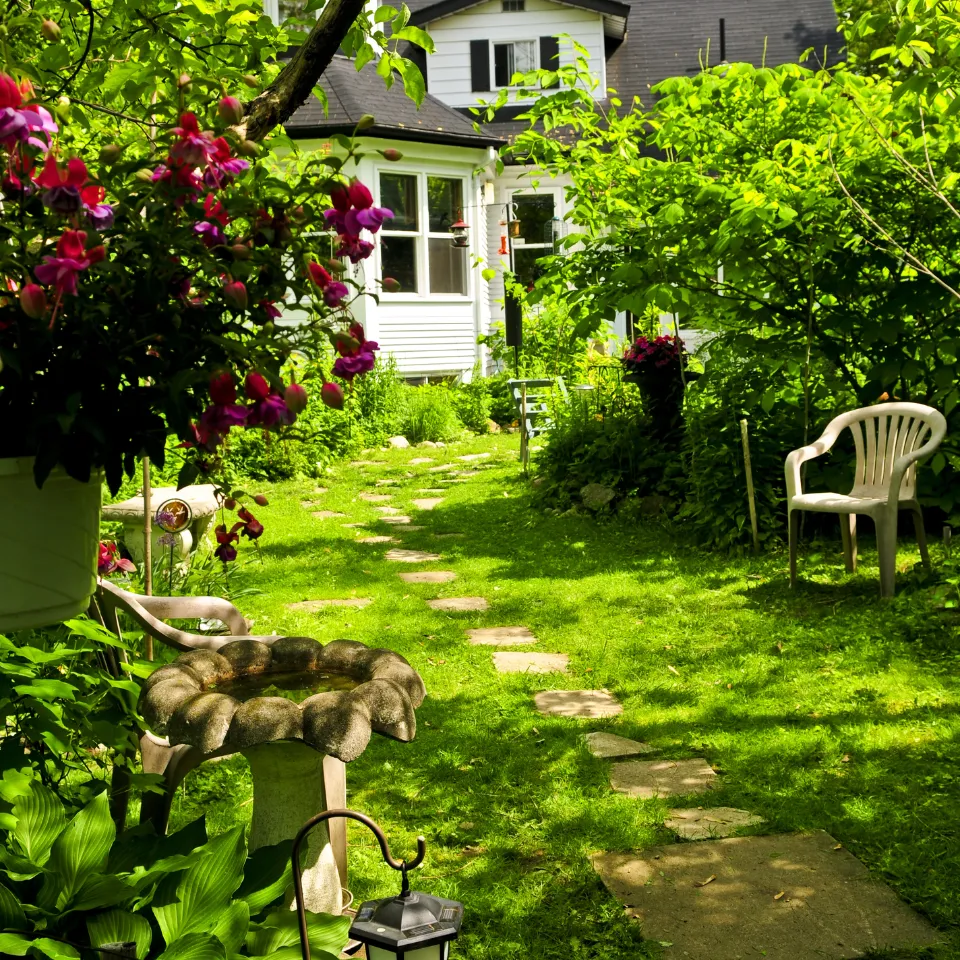 Home with blooming flowers and ‘For Sale’ sign, symbolizing spring real estate activity.