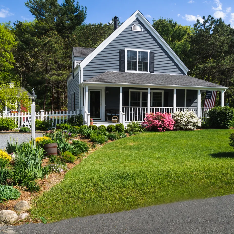 Sunny suburban home with a 'For Sale' sign in early summer, showcasing peak curb appeal and market timing.